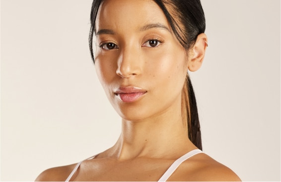 need alt text Woman with smooth, full cheeks and a defined jawline looking at the camera against a neutral background, illustrating facial rejuvenation after GLP-1 weight loss