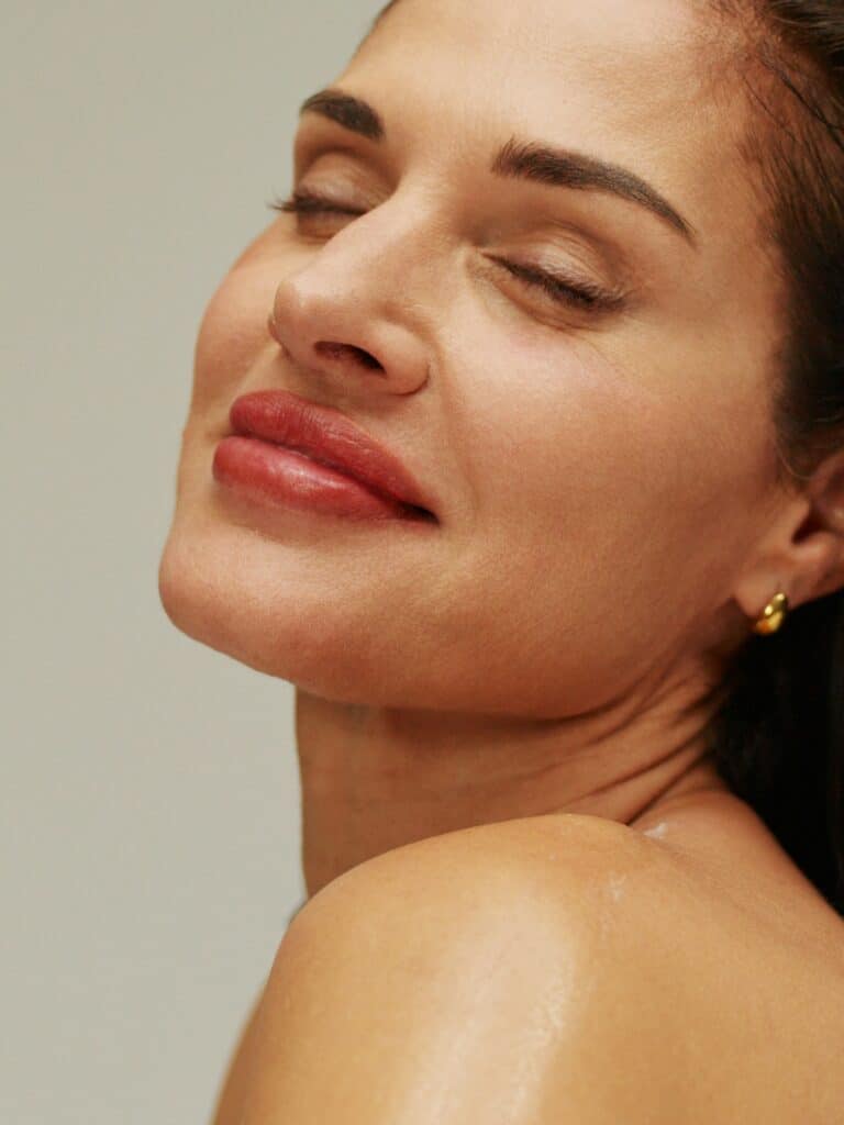 Woman with glowing skin and red lips shown in close-up portrait